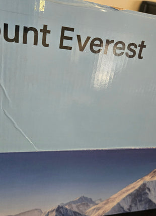 A close-up of a product box featuring the text 'Mount Everest' in dark brown lettering on a light blue background, with a printed mountain landscape image along the bottom.