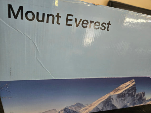 A close-up of a product box featuring the text 'Mount Everest' in dark brown lettering on a light blue background, with a printed mountain landscape image along the bottom.