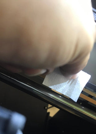 Creek Manufacturing Lint Free Wipes held by a beige hand, white wipe against gray DTG printer interior—DTG Printer Parts